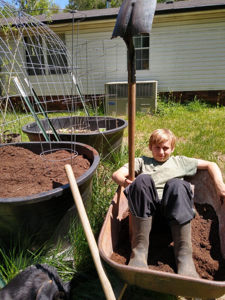 picture of Korban holding a shovel and relaxing in a wheelbarrow.