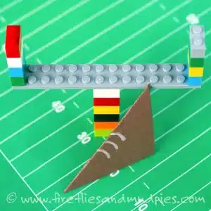 colorful lego goalpost and paper football on a green paper field