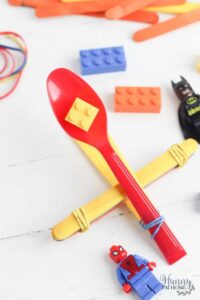 yellow lego on a red plastic spoon catapult