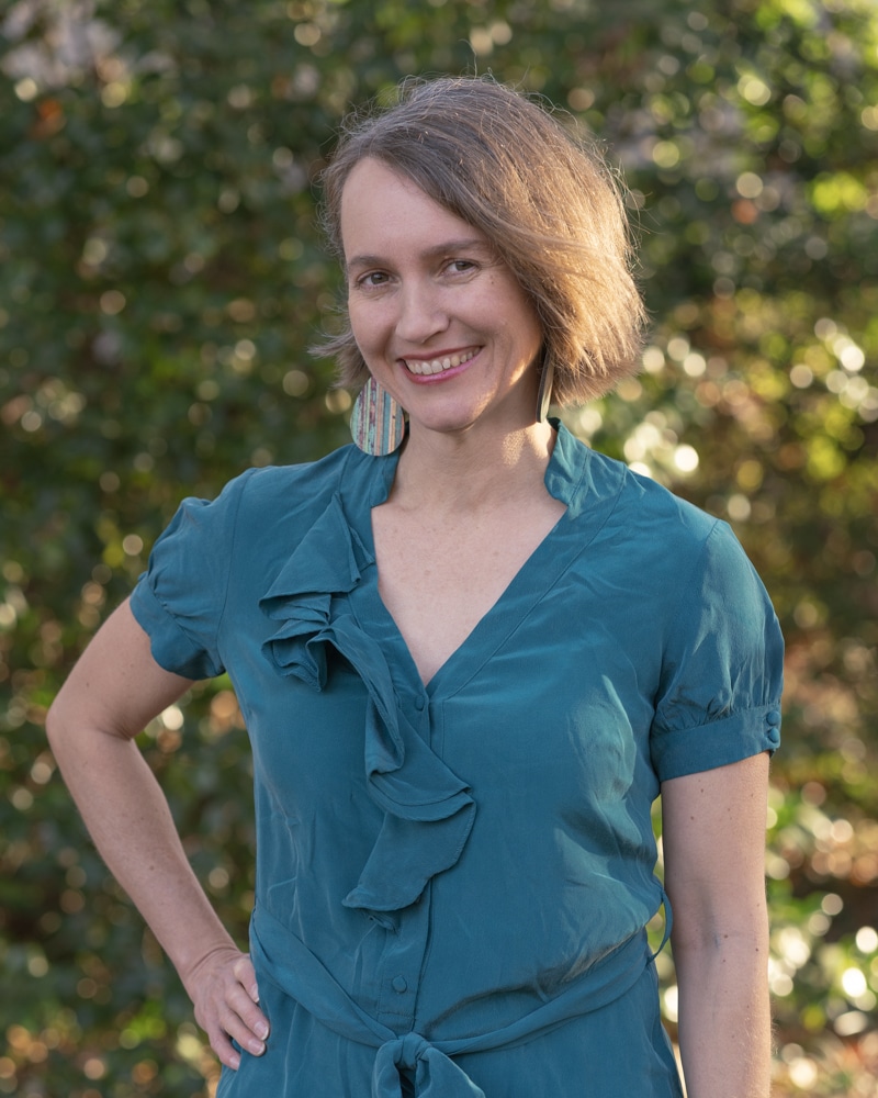 Danielle Papageorgiou standing with hand on hip in a turquoise shirt with trees in the background.